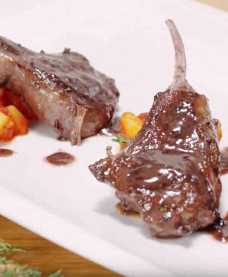 Chuletas de cordero sobre patatas estofadas con tomate